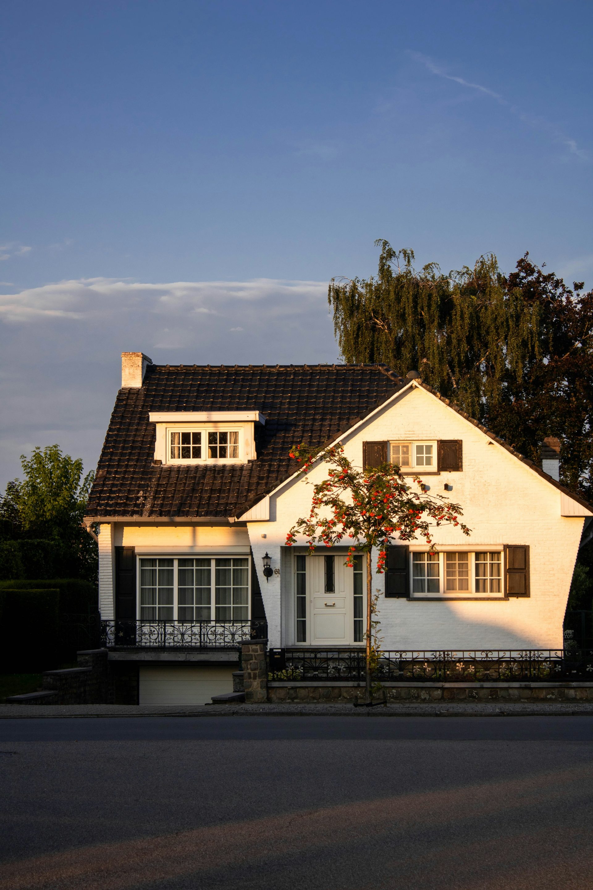white and brown concrete house near green trees under blue sky during daytime